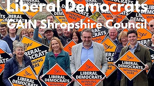 A group of Shropshire Lib Dems with signs stating "Liberal Democrats winning here"