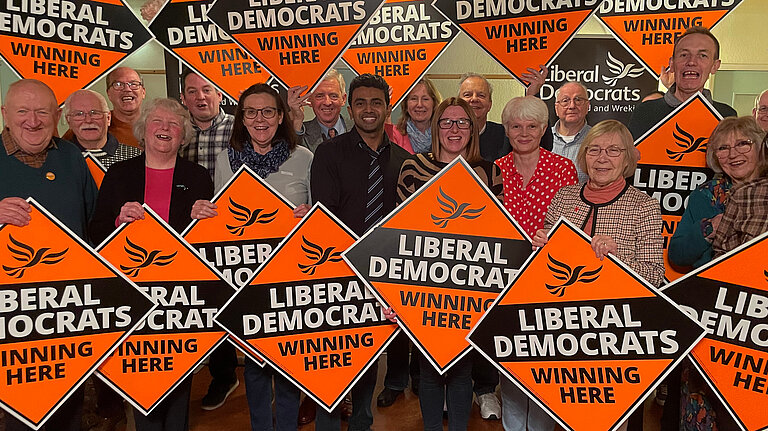 Members with signs saying "Lib Dems winning here"